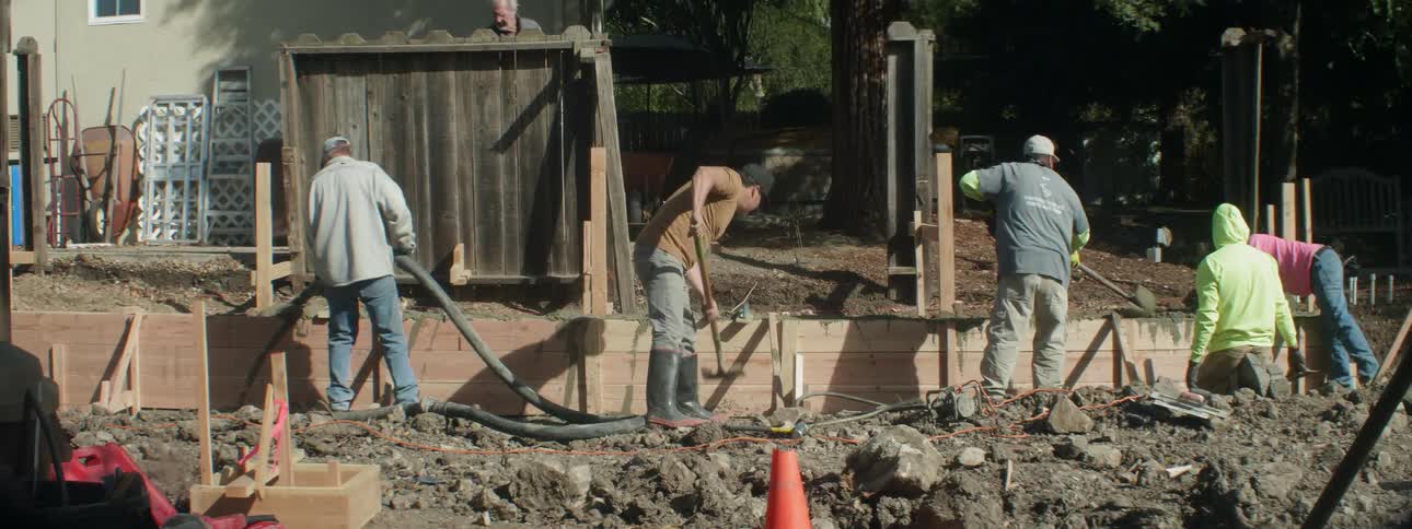 Workers are building a retaining wall outside a home during the day