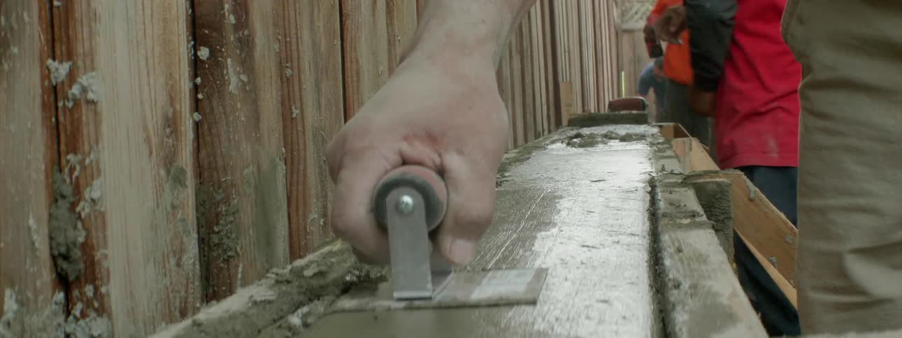 A construction worker smooths wet concrete