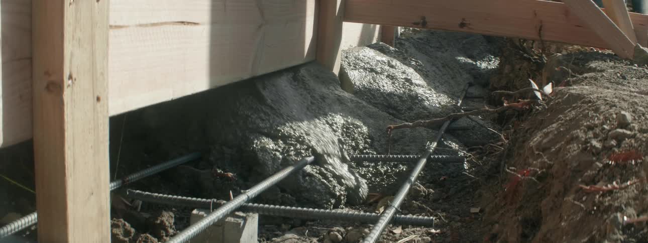 The cement is pouring in covering the rebar poles
