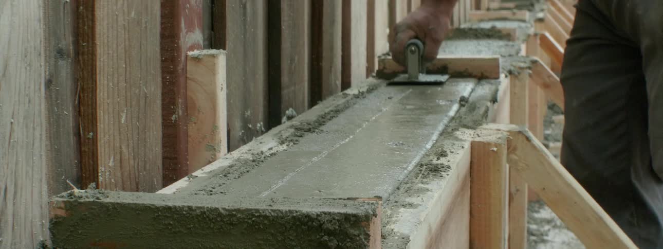 A worker uses a trowel to smooth out the cement