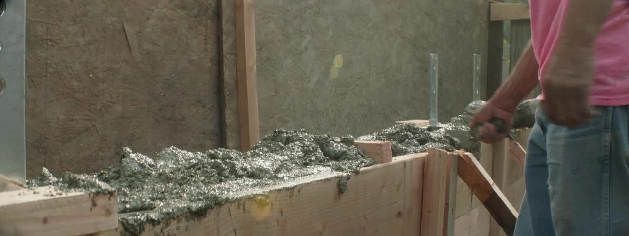 Construction worker lays concrete at a job site