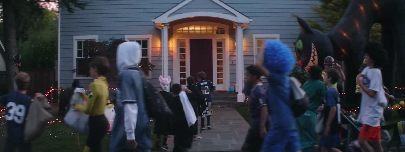 Children are trick or treating passing by and stopping at a home
