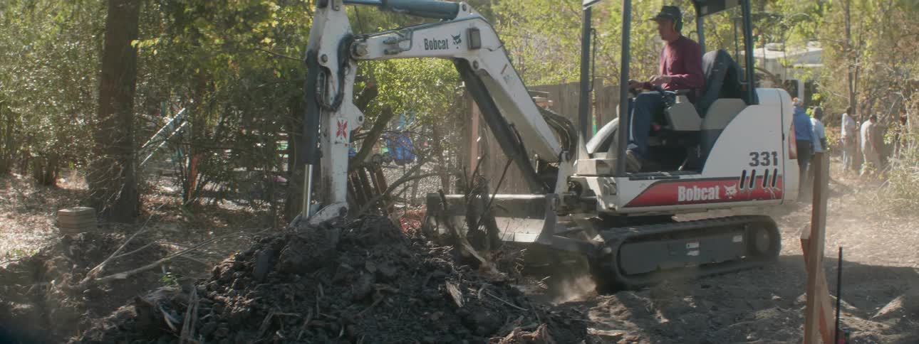A construction worker operates a digger at a job site