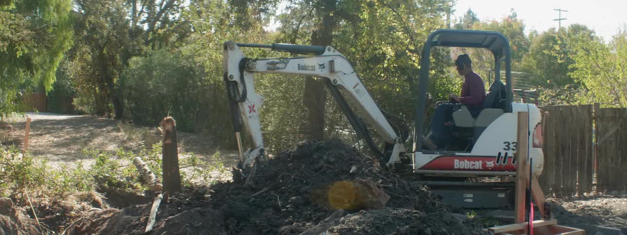 A construction worker operates a digger on a job site