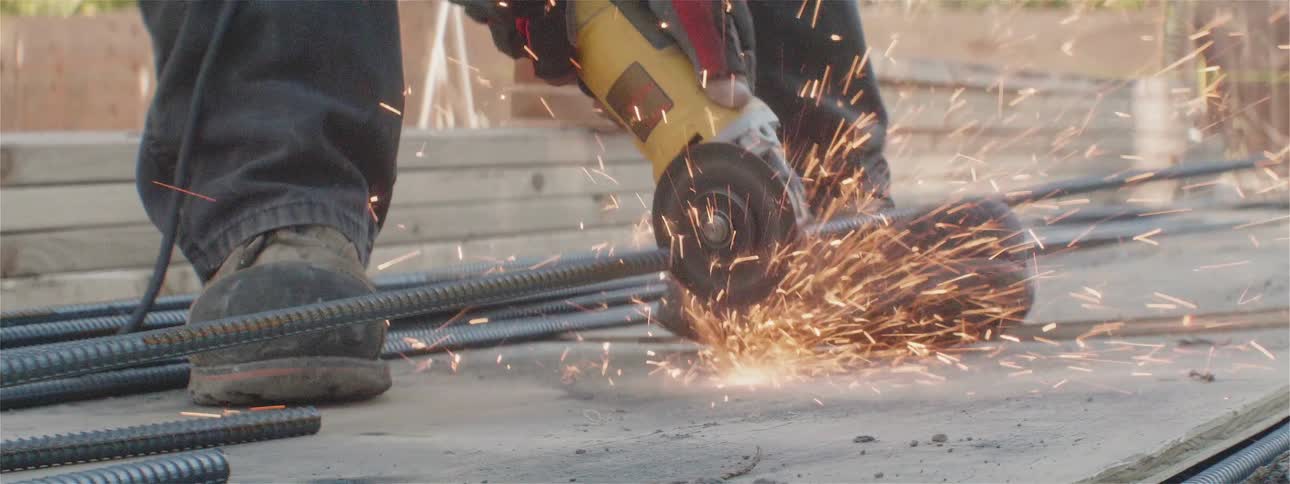 A man is using a saw to cut metal bars