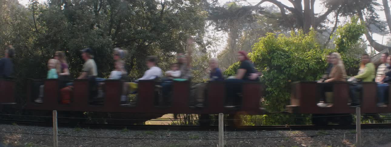 People are riding on a miniature train outside during the day