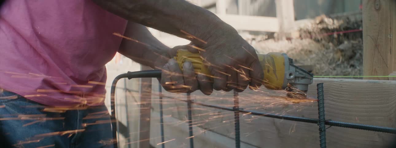 A construction worker saws metal on a job site