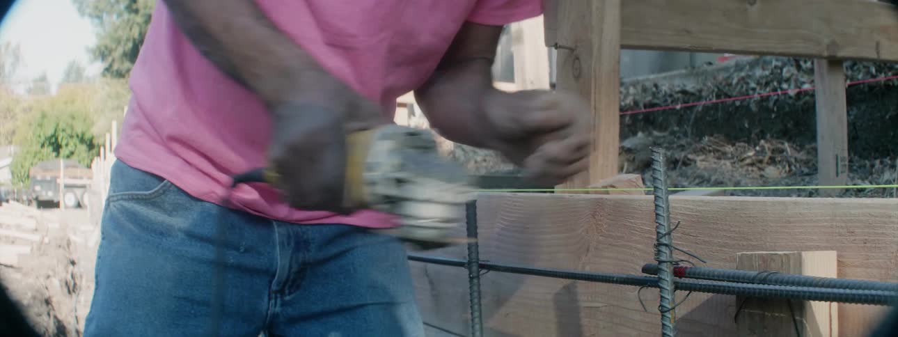 A construction worker saws metal on a job site