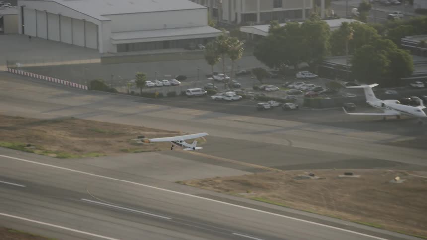 Small airplane takes off over a tree covered city