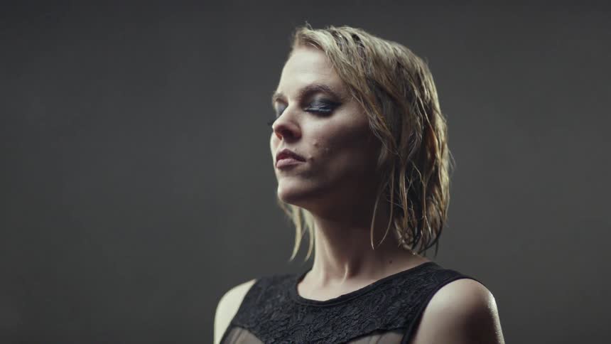 A clothed woman is dripping wet with her eyes closed