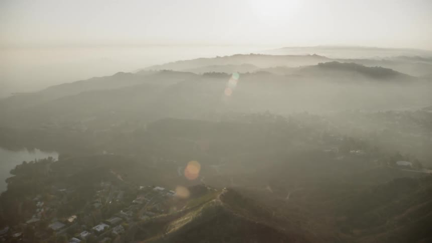 Sunlight shines over a valley on a foggy day