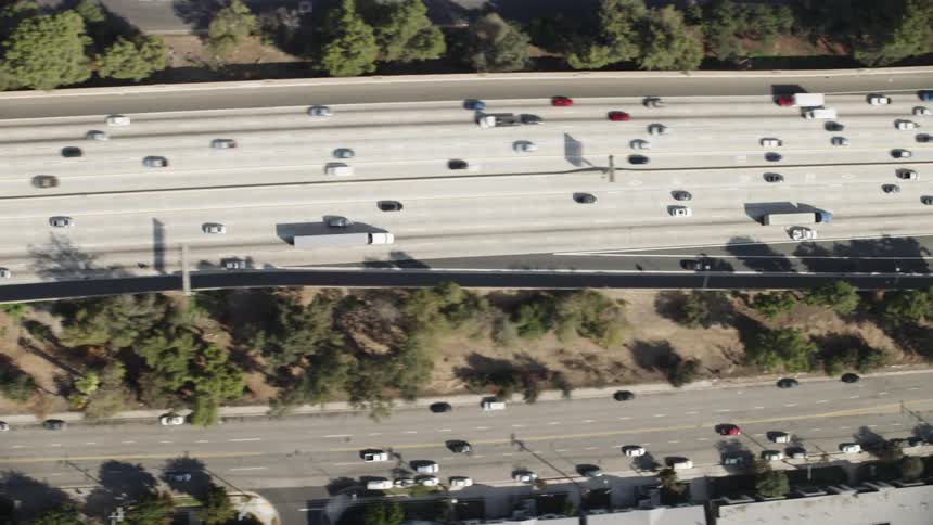 Cars travel on a highway overpass above the traffic and streets below