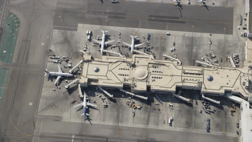 Airplanes are waiting at terminal gates in an airport during the day
