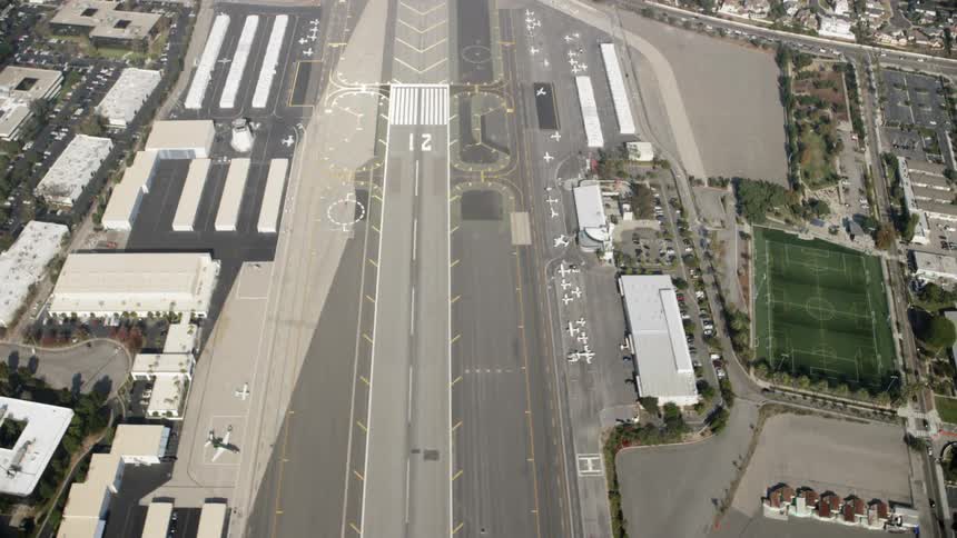 Airplanes are sitting waiting near hangars at an airport during the day
