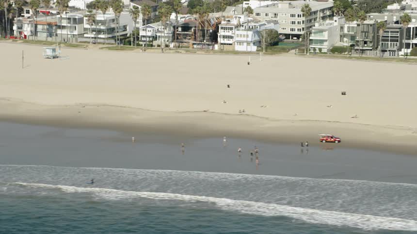 A lifeguard vehicle drives on a beach during the day