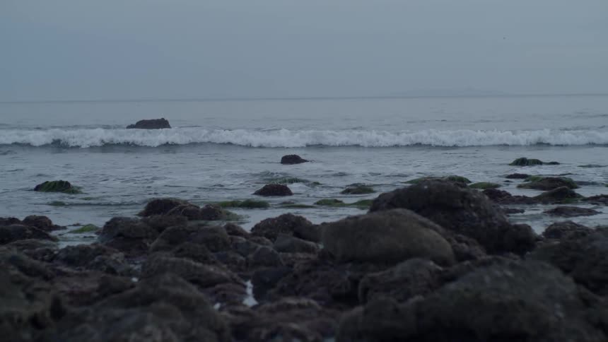 The small waves crash against the rock