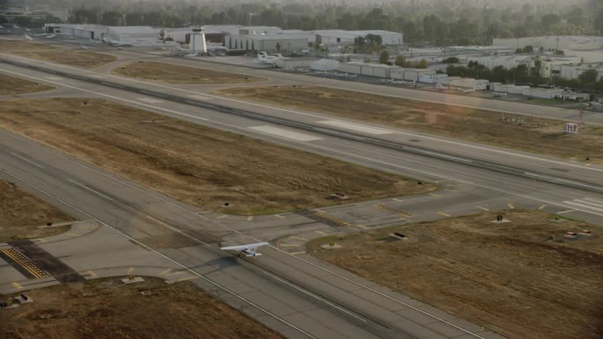 An small airplane lands on an airport landing strip
