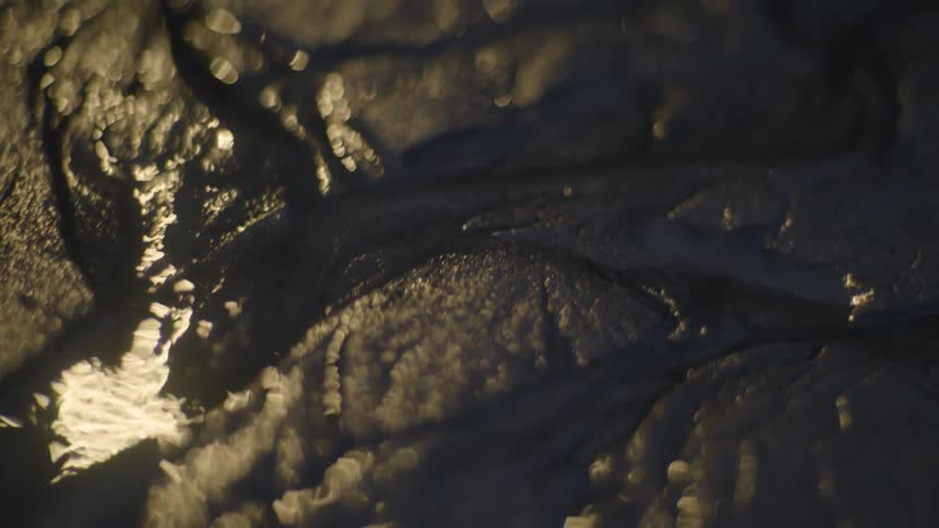 Water is trickling across a surface outside at night
