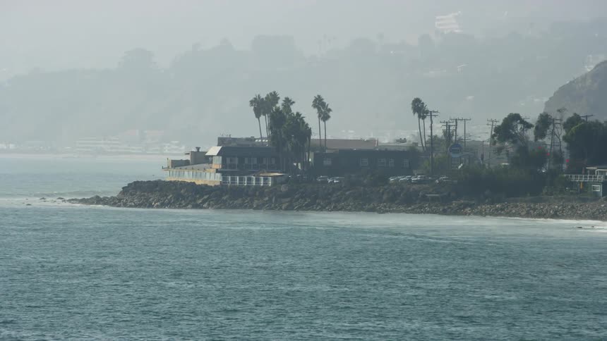 The water crashes against the shore on a foggy day