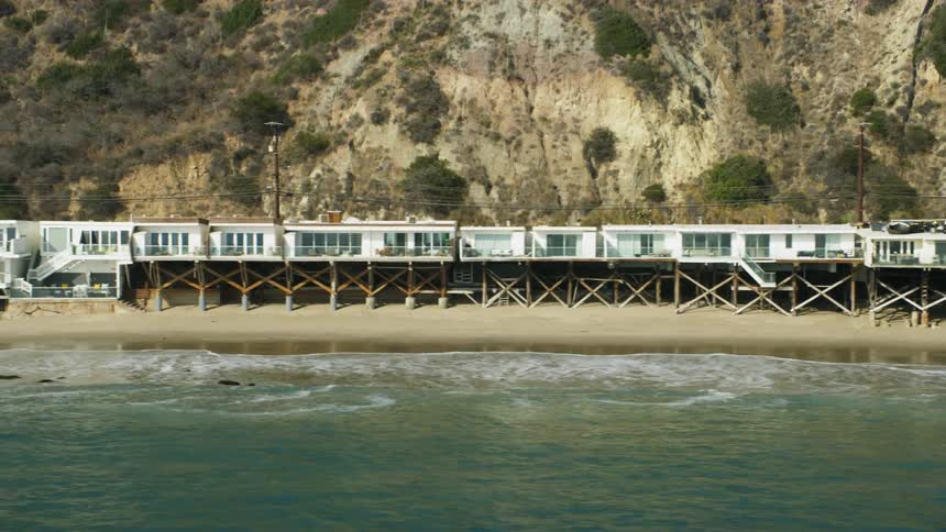 Houses are close to the water of the beach by a road