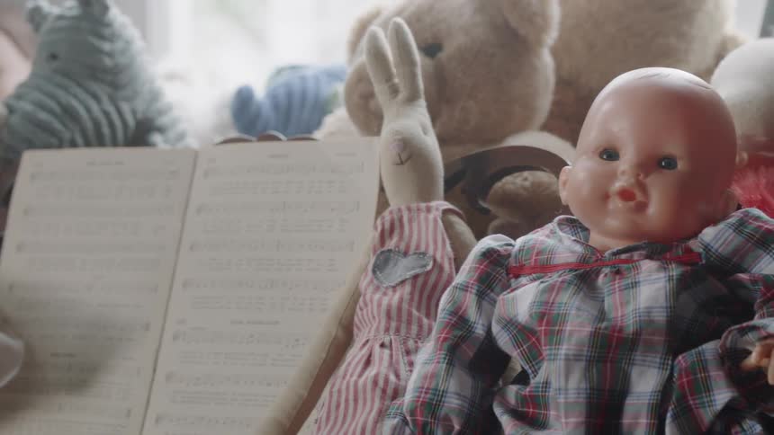 Dolls and stuffed animals surround sheet music