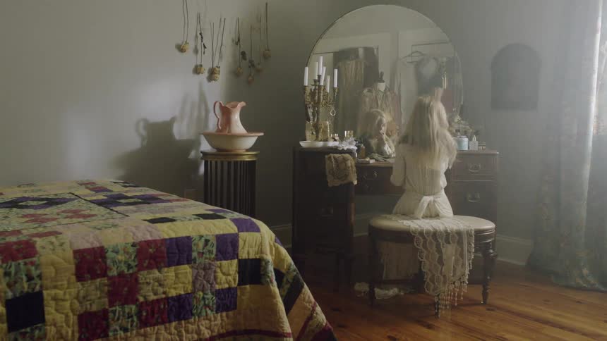 A child is sitting in front of a mirror in the bedroom