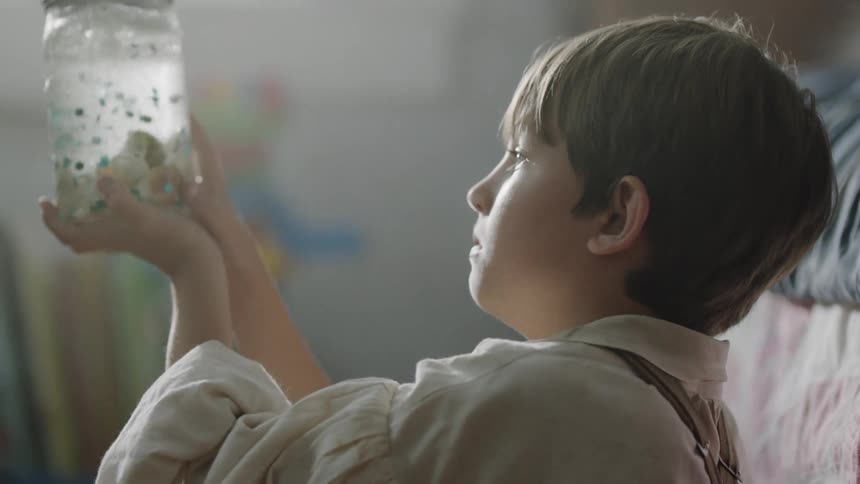 A boy shakes a jar and watches the contents settle