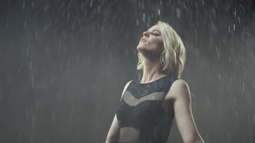 A woman leans her head back as water rains down on her