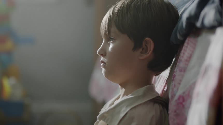 A young boy sits on the floor of a bedroom