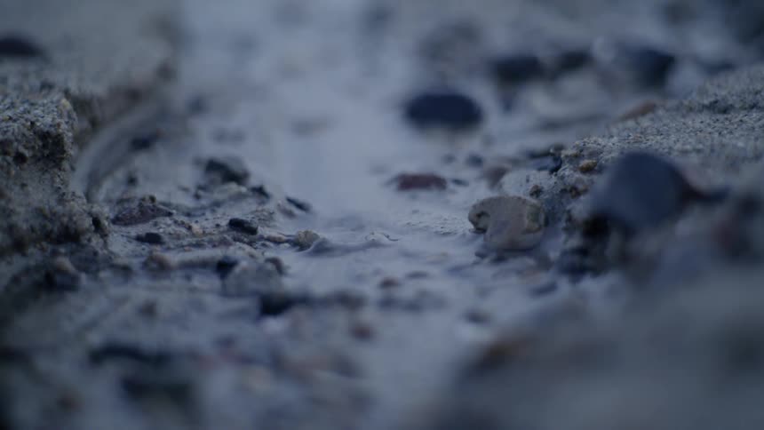 A trickle of water flows over sand