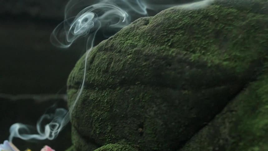 Smoke from incense is swirling up into the air above a shrine