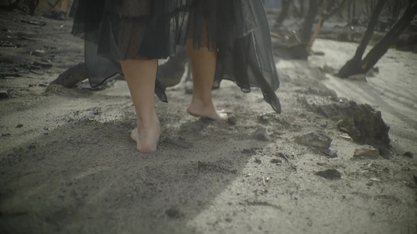 A woman walks barefoot over dirt