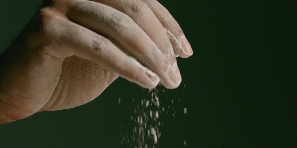 A man sprinkles flour and gets it off his fingers