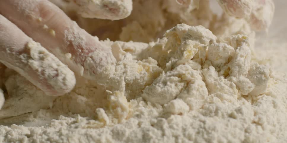 A person kneads dough with their hands