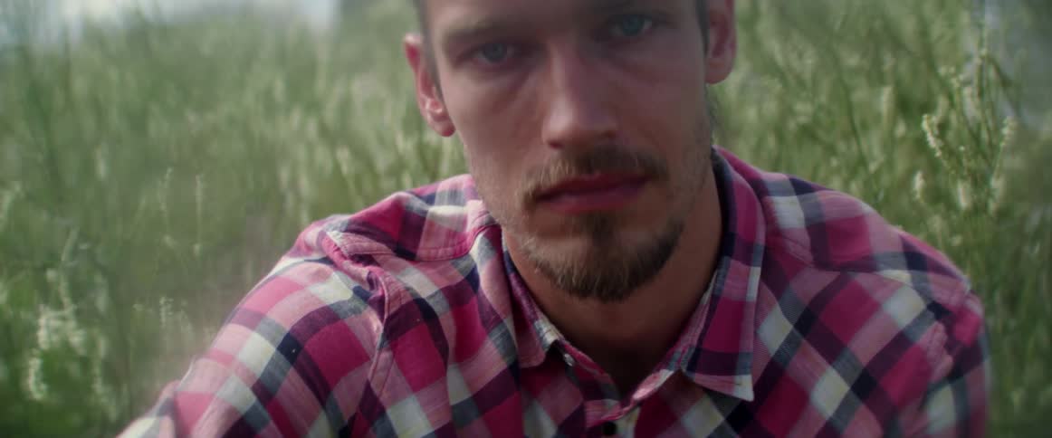 A thoughtful young explorer processes his emotions while resting in a wild field.