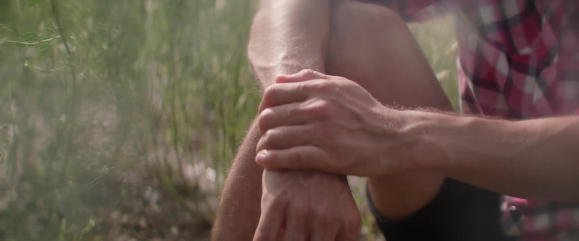 A male adventurer sits among the yarrow weeds during a summer trip.