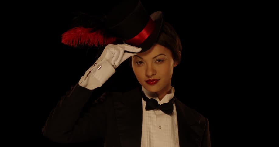A woman wears a top hat and tuxedo