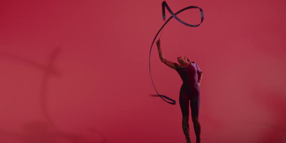 A woman performs a rhythmic gymnastic routine with a ribbon