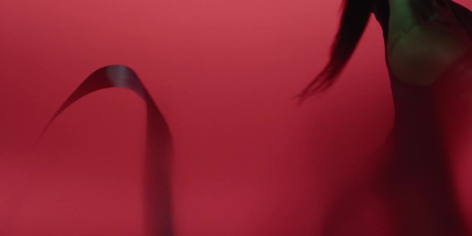 A woman is performing a routine using a ribbon in as smoke swirls around her