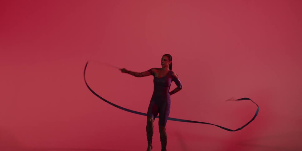 A woman is doing a ribbon dance in a red room