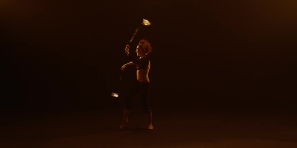 A performer spins balls of fire on chains