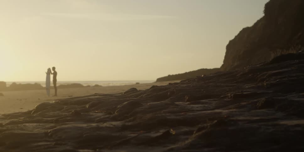 Two people stand on the beach on a cloudy day
