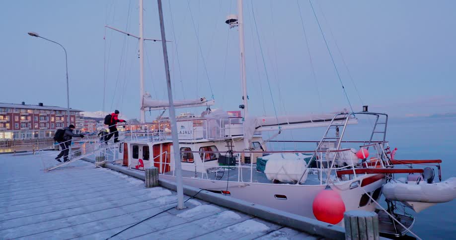 Two people walk down a dock and onto a ship
