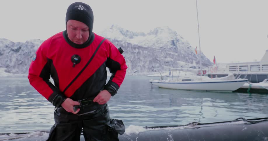 Man stands outside by water and fastens belt