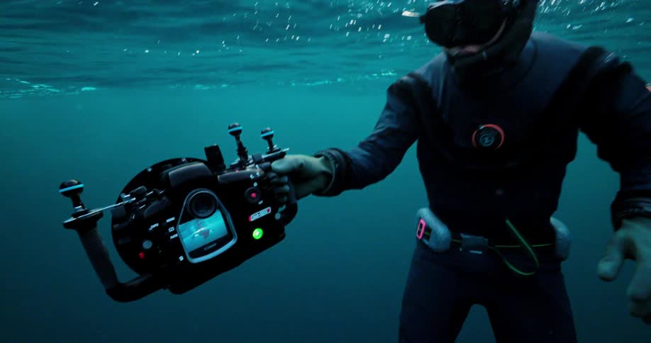 Person underwater holds a camera