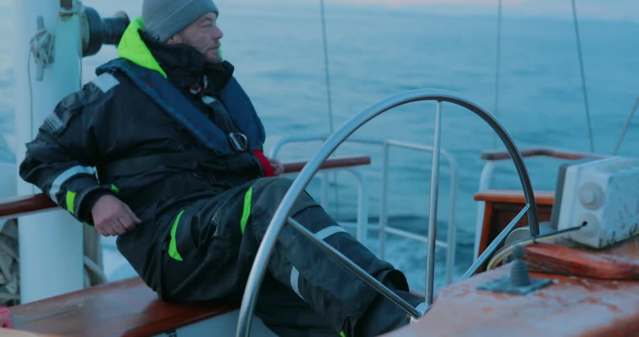 A man leans back and steers a boat with his foot