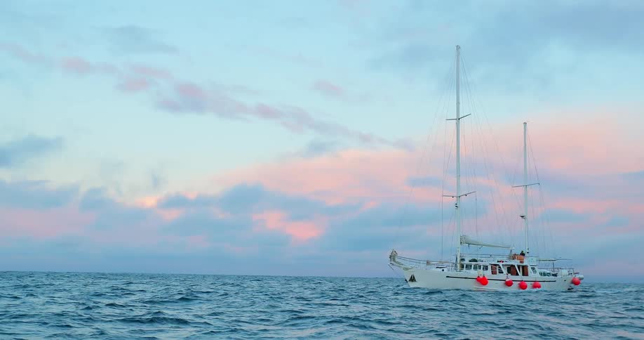 A boat moves through the ocean at sunset