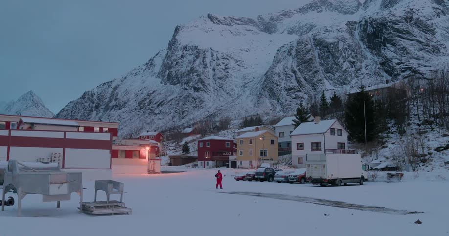 A man walks through the snow by snow covered mountains