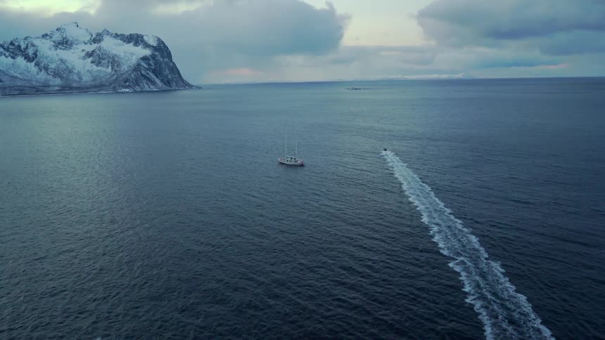 A dinghy is speeding out into the ocean in winter at dawn