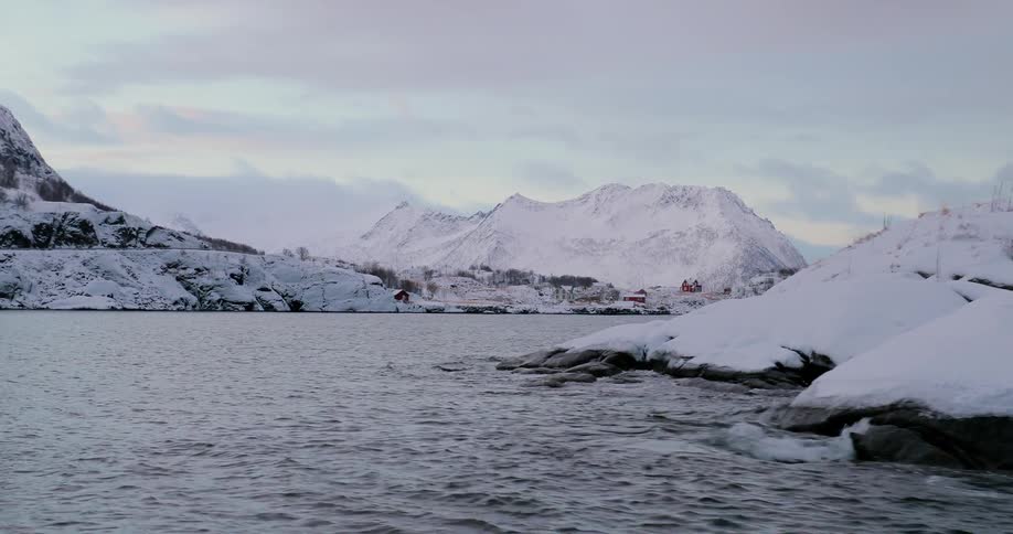 Waves gently crash onto the snow covered mountain shore